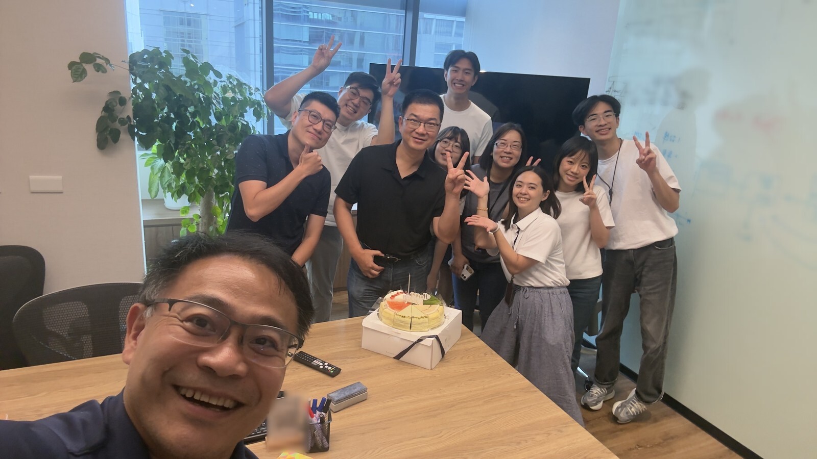 Zettabyte team members smile and make peace signs around a table in a meeting room at the Taipei office, with one colleague taking the selfie in the foreground.