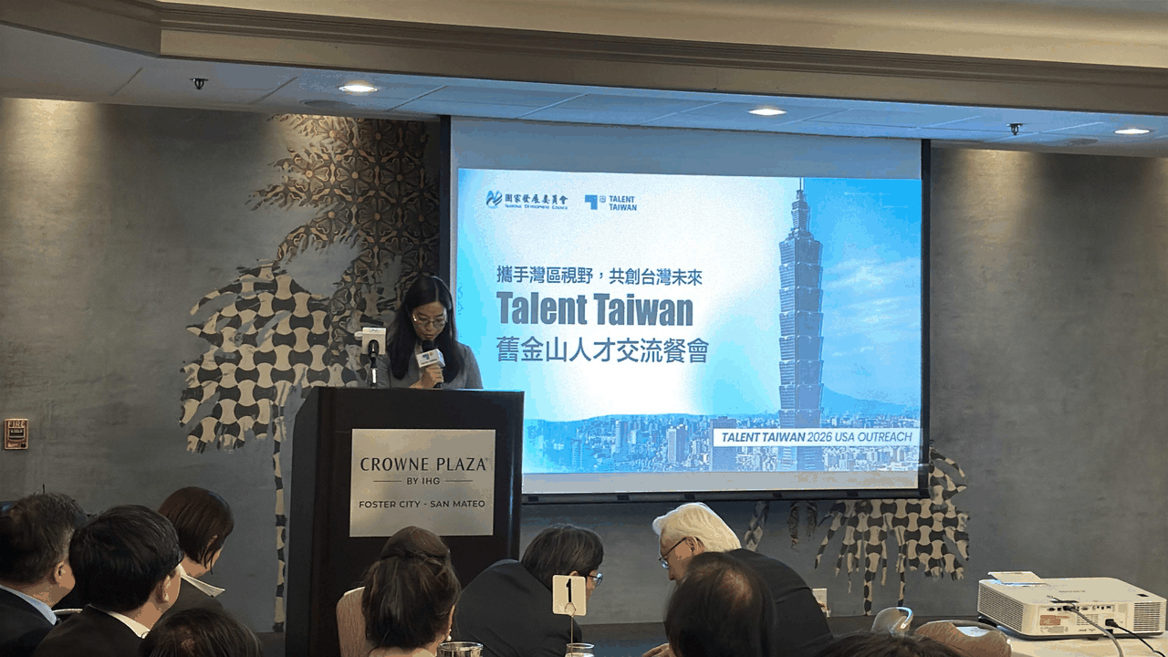 A speaker at a podium beside a screen showing the National Development Council and Talent Taiwan logos and the title of the Talent Taiwan San Francisco talent exchange dinner